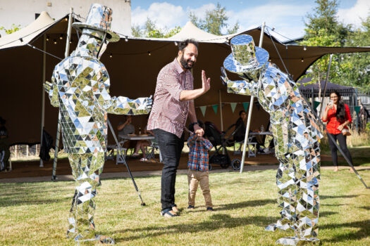two people covered in mirrors high-five a man with a small child
