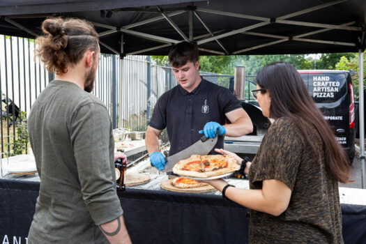 man serves pizza to two people